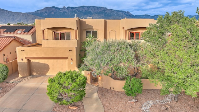 9404 Bear Mountain Trl NE, Albuquerque, NM 87113 - adobe home with a mountain view, stucco siding, concrete driveway, an attached garage, and a gate