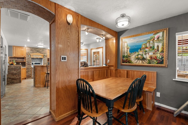 1217 Cagua Dr NE, Albuquerque, NM 87110 - dining area featuring a textured ceiling, arched walkways, a fireplace, and light wood-style flooring