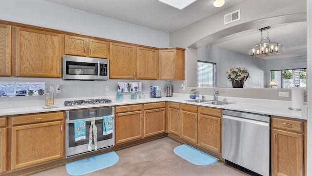 3915 Tundra Swan Ct NW, Albuquerque, NM 87120 - kitchen with appliances with stainless steel finishes, finished concrete flooring, light countertops, arched walkways, and hanging light fixtures