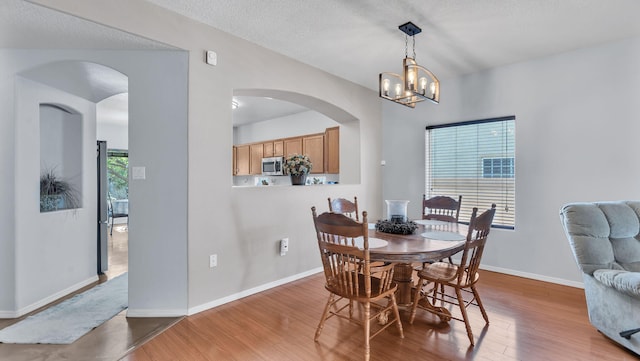 3915 Tundra Swan Ct NW, Albuquerque, NM 87120 - dining room with wood finished floors, a chandelier, arched walkways, and a textured ceiling