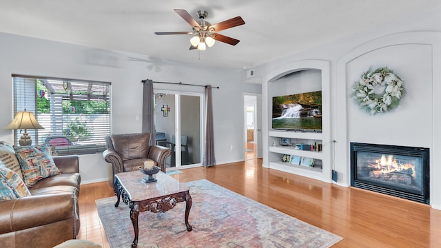 3915 Tundra Swan Ct NW, Albuquerque, NM 87120 - living area with a glass covered fireplace, wood finished floors, a ceiling fan, and built in features