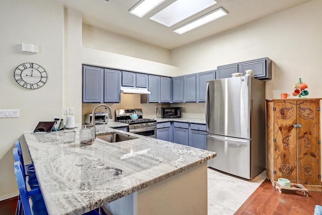 640 Renaissance Loop SE, Rio Rancho, NM 87124 - kitchen featuring stainless steel appliances, a peninsula, light stone counters, a high ceiling, and under cabinet range hood
