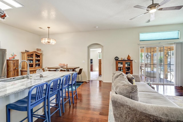 640 Renaissance Loop SE, Rio Rancho, NM 87124 - kitchen featuring arched walkways, dark wood-type flooring, freestanding refrigerator, light stone countertops, and a ceiling fan