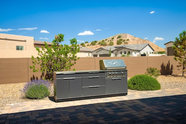 5402 Grays Peak Trl NE, Rio Rancho, NM 87144 - fenced backyard featuring a mountain view, exterior kitchen, and a patio area