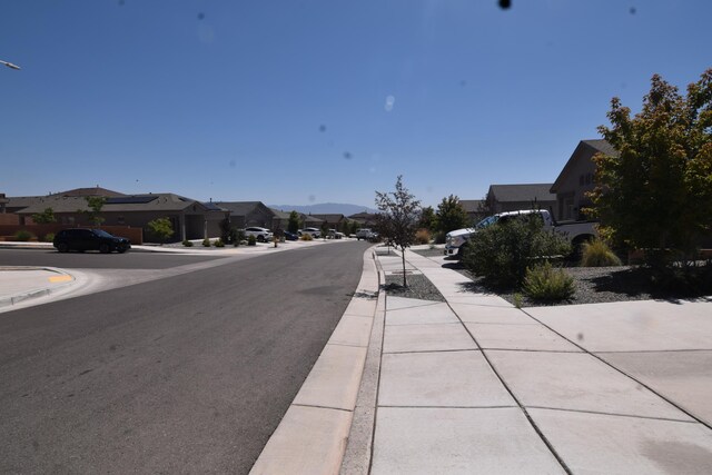 10812 Caresso SW, Albuquerque, NM 87121 - view of asphalt street featuring sidewalks, a residential view, curbs, and street lights