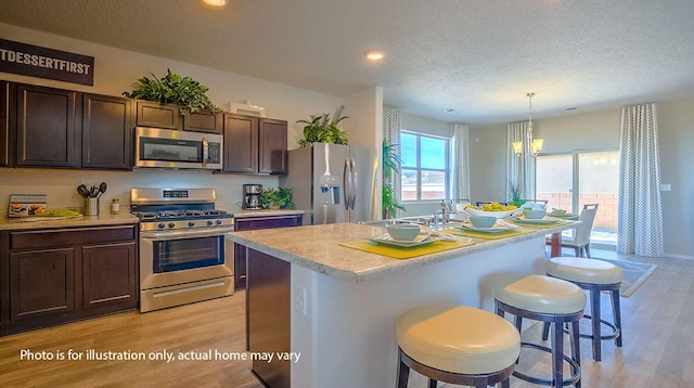 1652 Maggie Ct NE, Rio Rancho, NM 87144 - kitchen featuring stainless steel appliances, a textured ceiling, light wood finished floors, a breakfast bar, and light countertops