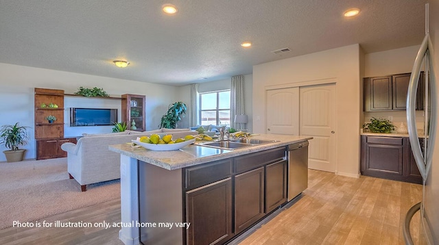 1652 Maggie Ct NE, Rio Rancho, NM 87144 - kitchen featuring stainless steel appliances, open floor plan, light wood-type flooring, a textured ceiling, and a kitchen island with sink