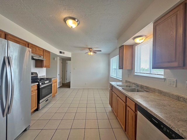 5612 Territorial Rd NW, Albuquerque, NM 87120 - kitchen featuring appliances with stainless steel finishes, under cabinet range hood, a textured ceiling, a ceiling fan, and brown cabinets