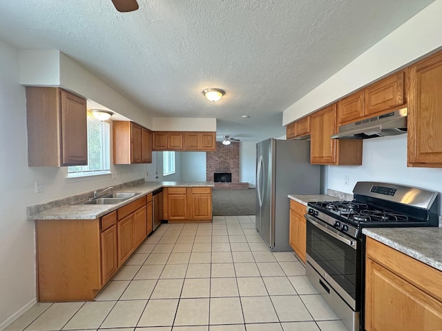 5612 Territorial Rd NW, Albuquerque, NM 87120 - kitchen with appliances with stainless steel finishes, under cabinet range hood, a ceiling fan, a textured ceiling, and a brick fireplace