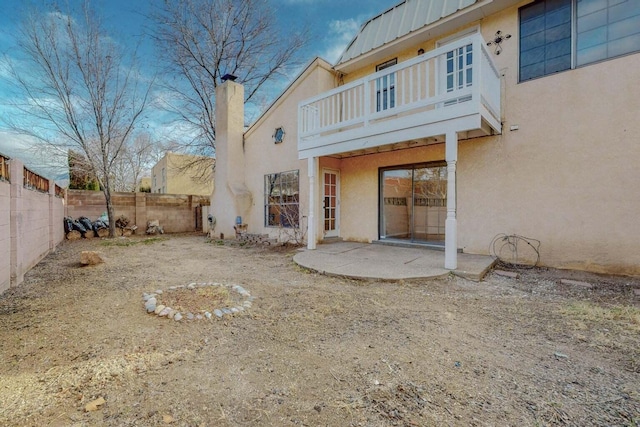9815 Osuna Rd NE, Albuquerque, NM 87111 - rear view of house featuring a balcony, stucco siding, a fenced backyard, a chimney, and a metal roof