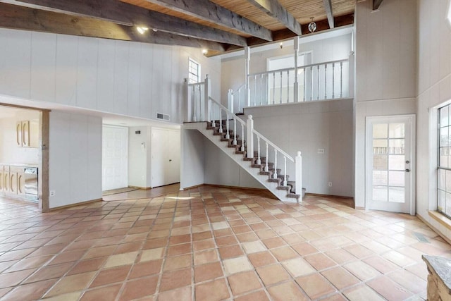 9815 Osuna Rd NE, Albuquerque, NM 87111 - unfurnished living room with a towering ceiling, stairs, tile patterned floors, and a wood ceiling with exposed beams