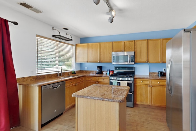 4249 Montera Pl NW, Albuquerque, NM 87114 - kitchen featuring appliances with stainless steel finishes, light wood-type flooring, a kitchen island, light stone counters, and track lighting