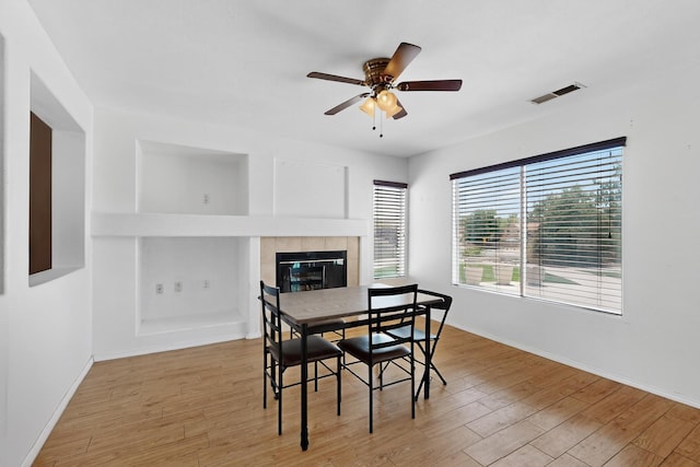 4249 Montera Pl NW, Albuquerque, NM 87114 - dining room featuring light wood-type flooring, a tiled fireplace, and a ceiling fan