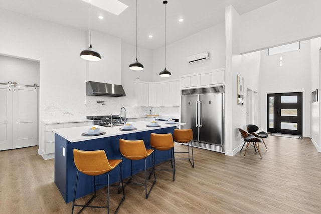 53 Blanco Dr, Edgewood, NM 87015 - kitchen with built in refrigerator, a high ceiling, wall chimney exhaust hood, an AC wall unit, and light countertops