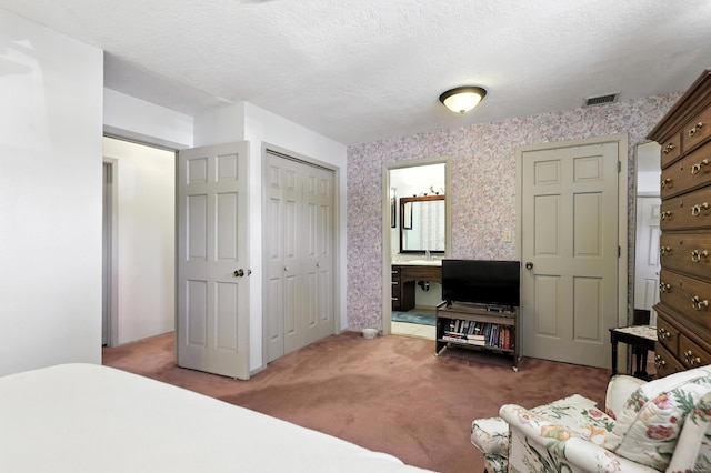 411 Schmidt Pl, Los Lunas, NM 87031 - bedroom featuring wallpapered walls, carpet flooring, ensuite bath, a closet, and a textured ceiling