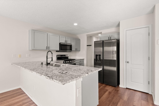 716 Palo Duro Dr, Bernalillo, NM 87004 - kitchen with appliances with stainless steel finishes, gray cabinetry, a peninsula, wood finished floors, and a textured ceiling