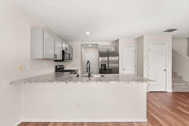 716 Palo Duro Dr, Bernalillo, NM 87004 - kitchen with stainless steel appliances, a peninsula, light wood-type flooring, a textured ceiling, and gray cabinetry