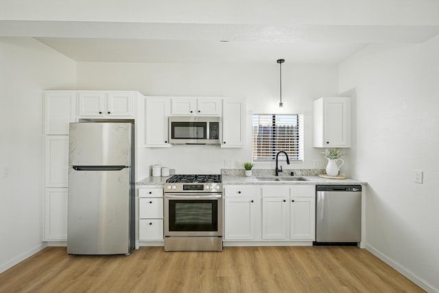 1202 Truman St SE, Albuquerque, NM 87108 - kitchen featuring stainless steel appliances, light wood finished floors, white cabinets, light stone countertops, and decorative light fixtures