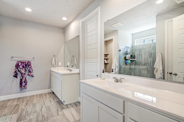 2530 Guadalupe Rd NE, Rio Rancho, NM 87144 - bathroom featuring a textured ceiling, two vanities, tiled shower, and recessed lighting