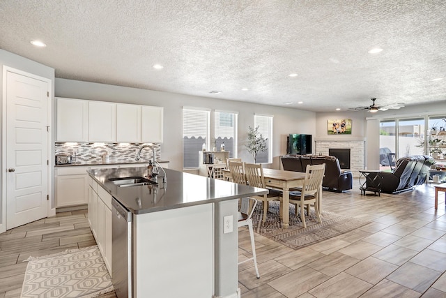 2530 Guadalupe Rd NE, Rio Rancho, NM 87144 - kitchen featuring a textured ceiling, recessed lighting, a ceiling fan, stainless steel dishwasher, and a stone fireplace