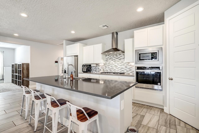 2530 Guadalupe Rd NE, Rio Rancho, NM 87144 - kitchen featuring appliances with stainless steel finishes, wall chimney exhaust hood, dark countertops, recessed lighting, and tasteful backsplash