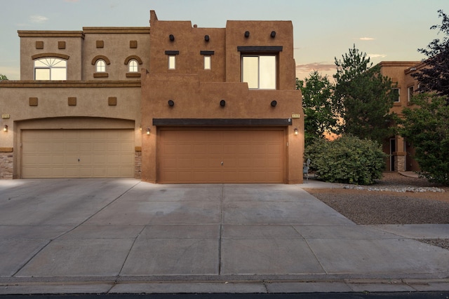 1717 Cortina Loop SE, Rio Rancho, NM 87124 - pueblo-style house with driveway, an attached garage, and stucco siding