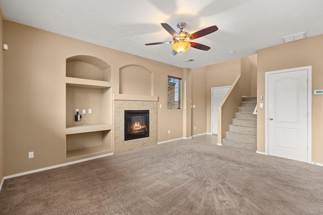 1717 Cortina Loop SE, Rio Rancho, NM 87124 - unfurnished living room featuring built in shelves, a textured ceiling, ceiling fan, carpet flooring, and a fireplace