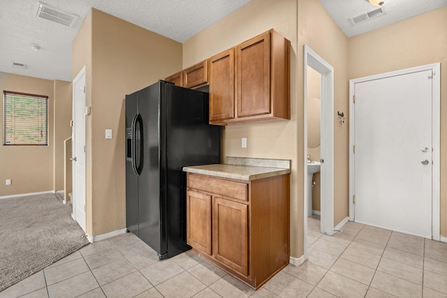 1717 Cortina Loop SE, Rio Rancho, NM 87124 - kitchen featuring light countertops, black fridge, a textured ceiling, brown cabinetry, and light tile patterned floors
