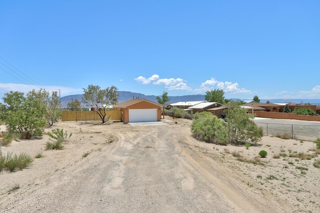 1004 11th St SE, Rio Rancho, NM 87124 - view of front of house with a garage, dirt driveway, and a mountain view