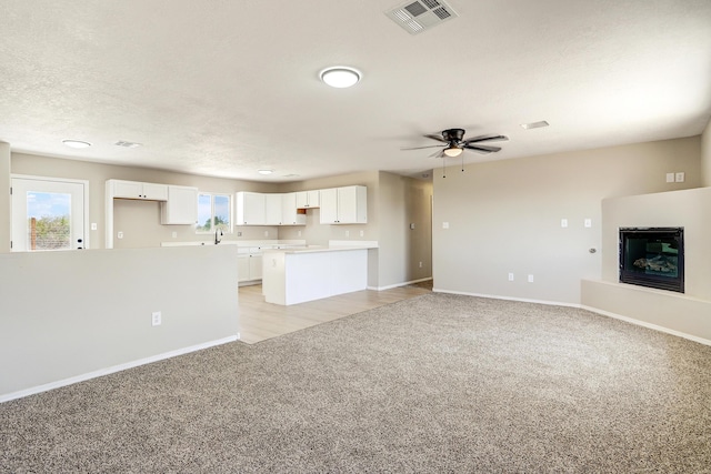 1004 11th St SE, Rio Rancho, NM 87124 - unfurnished living room featuring light carpet, a glass covered fireplace, and a ceiling fan