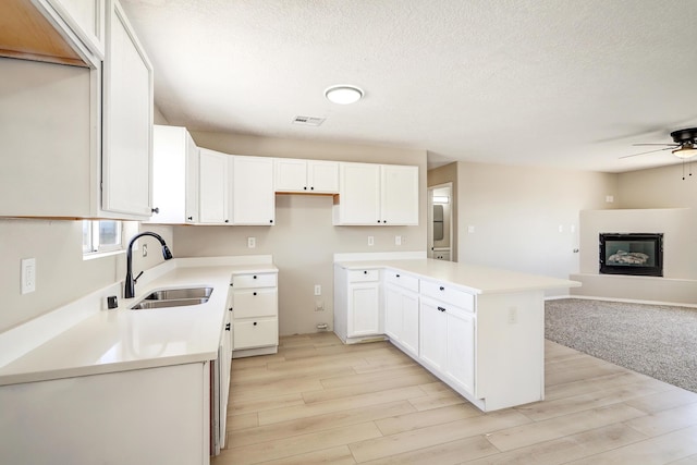 1004 11th St SE, Rio Rancho, NM 87124 - kitchen with ceiling fan, open floor plan, light wood-style flooring, a glass covered fireplace, and a textured ceiling