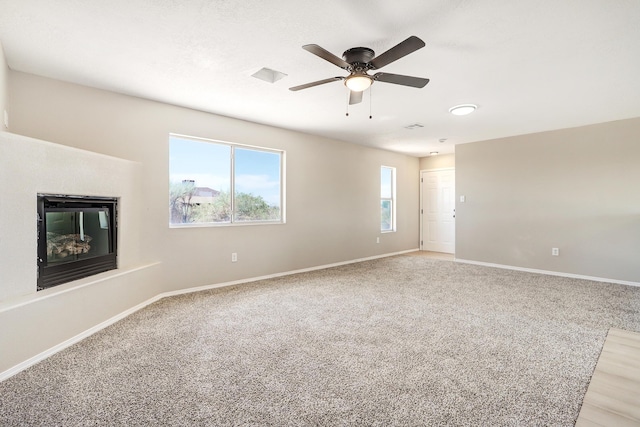 1004 11th St SE, Rio Rancho, NM 87124 - unfurnished living room featuring a ceiling fan, a glass covered fireplace, and light carpet