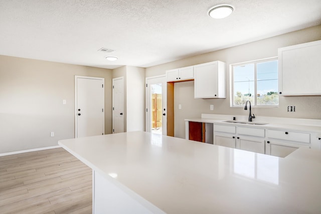 1004 11th St SE, Rio Rancho, NM 87124 - kitchen with light wood-style floors, white cabinetry, light countertops, and a textured ceiling
