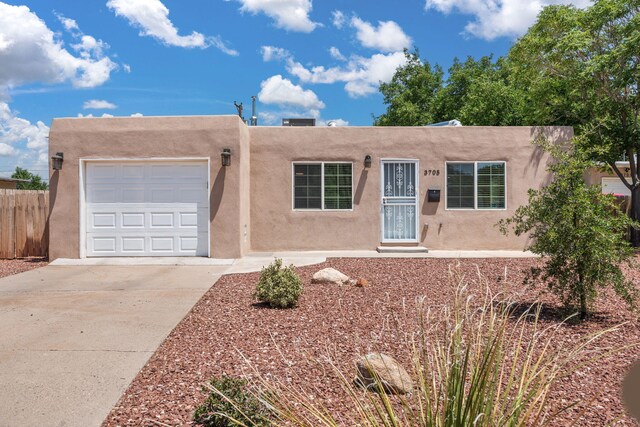3705 Palo Duro Ave NE, Albuquerque, NM 87110 - pueblo-style home featuring stucco siding, a garage, and driveway