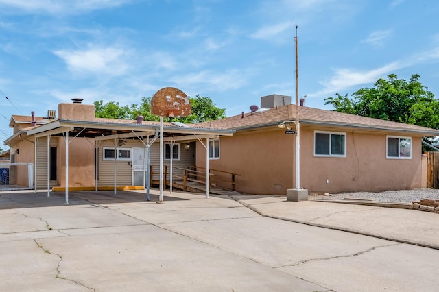 3921 Hilton Ave NE, Albuquerque, NM 87110 - back of house with a chimney, stucco siding, concrete driveway, and an attached carport