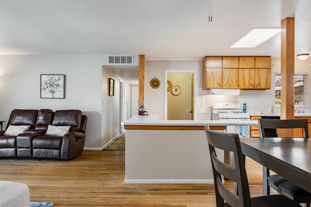 3921 Hilton Ave NE, Albuquerque, NM 87110 - kitchen with white gas range, under cabinet range hood, light wood-style floors, and light countertops