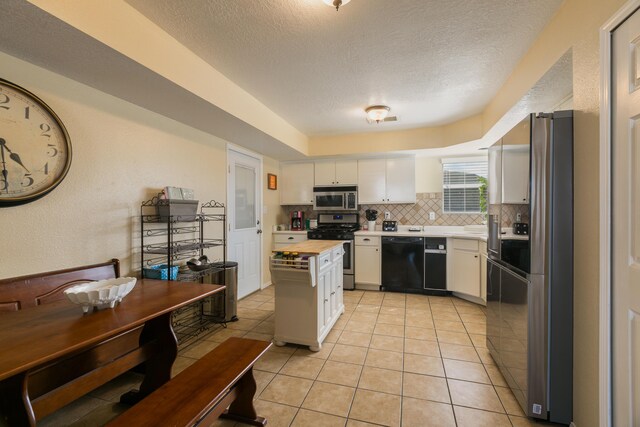 1897 Raspberry Ct NE, Rio Rancho, NM 87144 - kitchen featuring stainless steel appliances, backsplash, white cabinets, light tile patterned flooring, and a textured ceiling