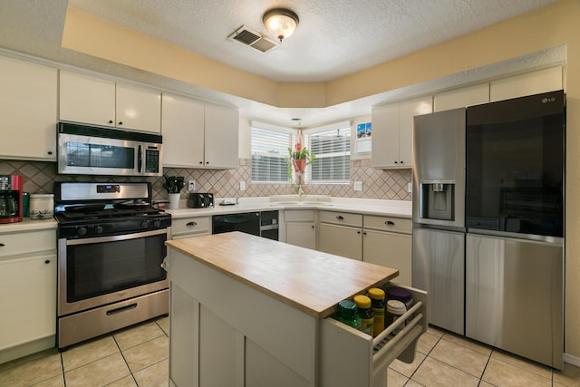 1897 Raspberry Ct NE, Rio Rancho, NM 87144 - kitchen with appliances with stainless steel finishes, light tile patterned floors, decorative backsplash, a textured ceiling, and a center island