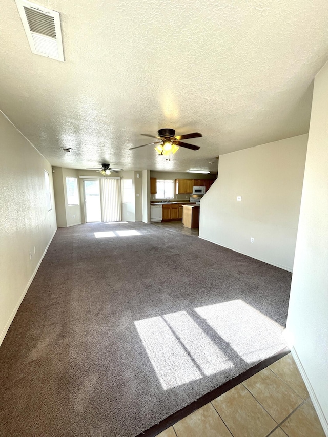 10608 Buck Island Rd SW, Albuquerque, NM 87121 - unfurnished living room with healthy amount of natural light, light carpet, a textured ceiling, and a ceiling fan