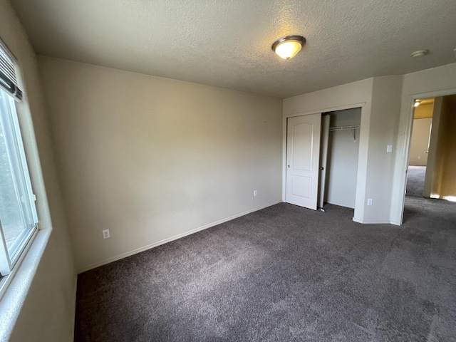 10608 Buck Island Rd SW, Albuquerque, NM 87121 - unfurnished bedroom with dark carpet, multiple windows, a textured ceiling, and a closet
