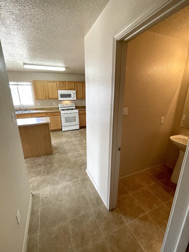 10608 Buck Island Rd SW, Albuquerque, NM 87121 - kitchen with white appliances, a textured ceiling, tile patterned flooring, light countertops, and a textured wall