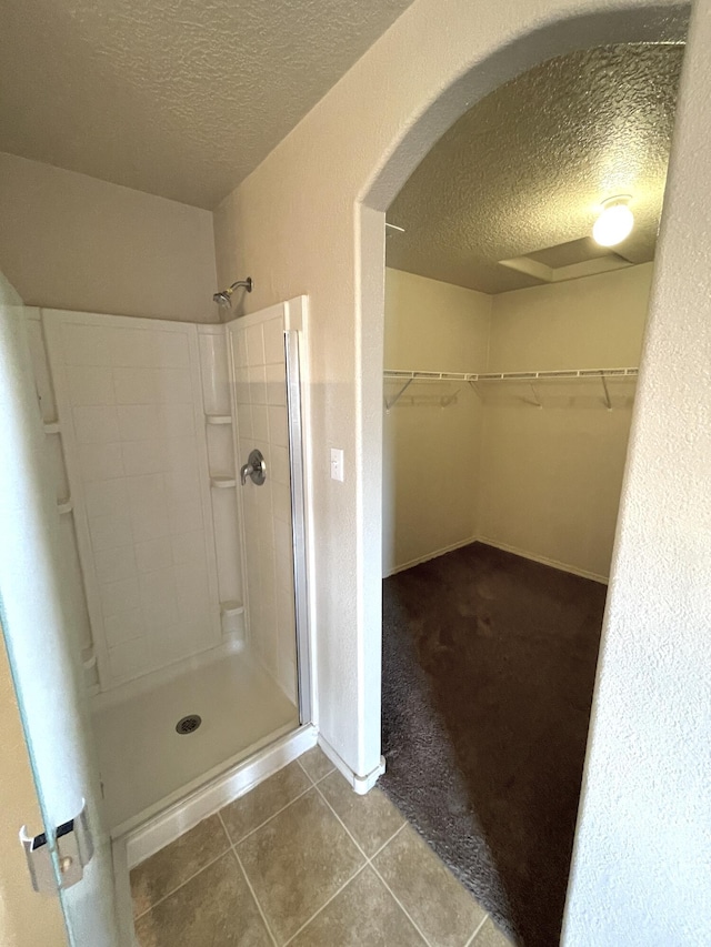 10608 Buck Island Rd SW, Albuquerque, NM 87121 - bathroom with a textured ceiling, a stall shower, a spacious closet, and tile patterned floors