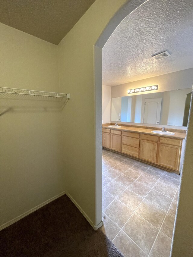 10608 Buck Island Rd SW, Albuquerque, NM 87121 - full bath with double vanity, a textured ceiling, a spacious closet, and tile patterned floors