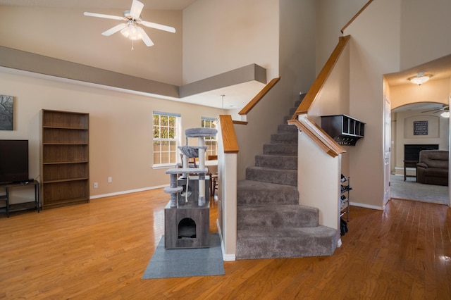 4840 Mcnary Ct NW, Albuquerque, NM 87120 - stairs featuring a ceiling fan, a towering ceiling, wood finished floors, arched walkways, and a wood stove