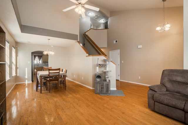 4840 Mcnary Ct NW, Albuquerque, NM 87120 - dining room featuring a chandelier, wood finished floors, a ceiling fan, a towering ceiling, and arched walkways