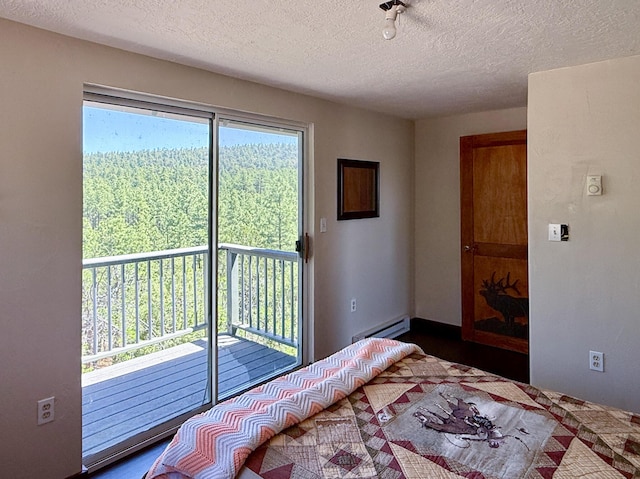 162 Black Bear Rd, Ramah, NM 87321 - bedroom with access to exterior, a textured ceiling, a baseboard heating unit, and a wooded view