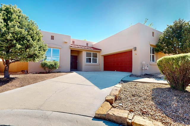 5 Woodflower Pl, Santa Fe, NM 87508 - southwest-style home with a standing seam roof, a garage, stucco siding, driveway, and a metal roof