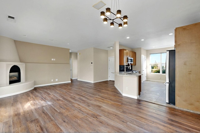 5 Woodflower Pl, Santa Fe, NM 87508 - unfurnished living room with wood finished floors, a chandelier, and recessed lighting