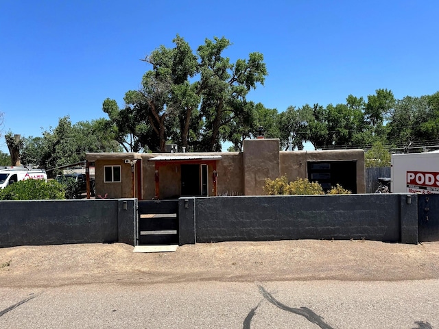 201 Marlowe Ln, Albuquerque, NM 87113 - pueblo-style home featuring a fenced front yard, a gate, and a chimney