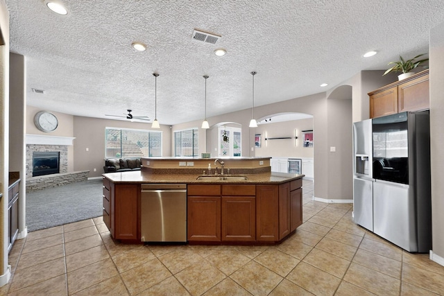 4420 Bentgrass Mdws NE, Rio Rancho, NM 87144 - kitchen with stainless steel appliances, arched walkways, open floor plan, an island with sink, and brown cabinetry